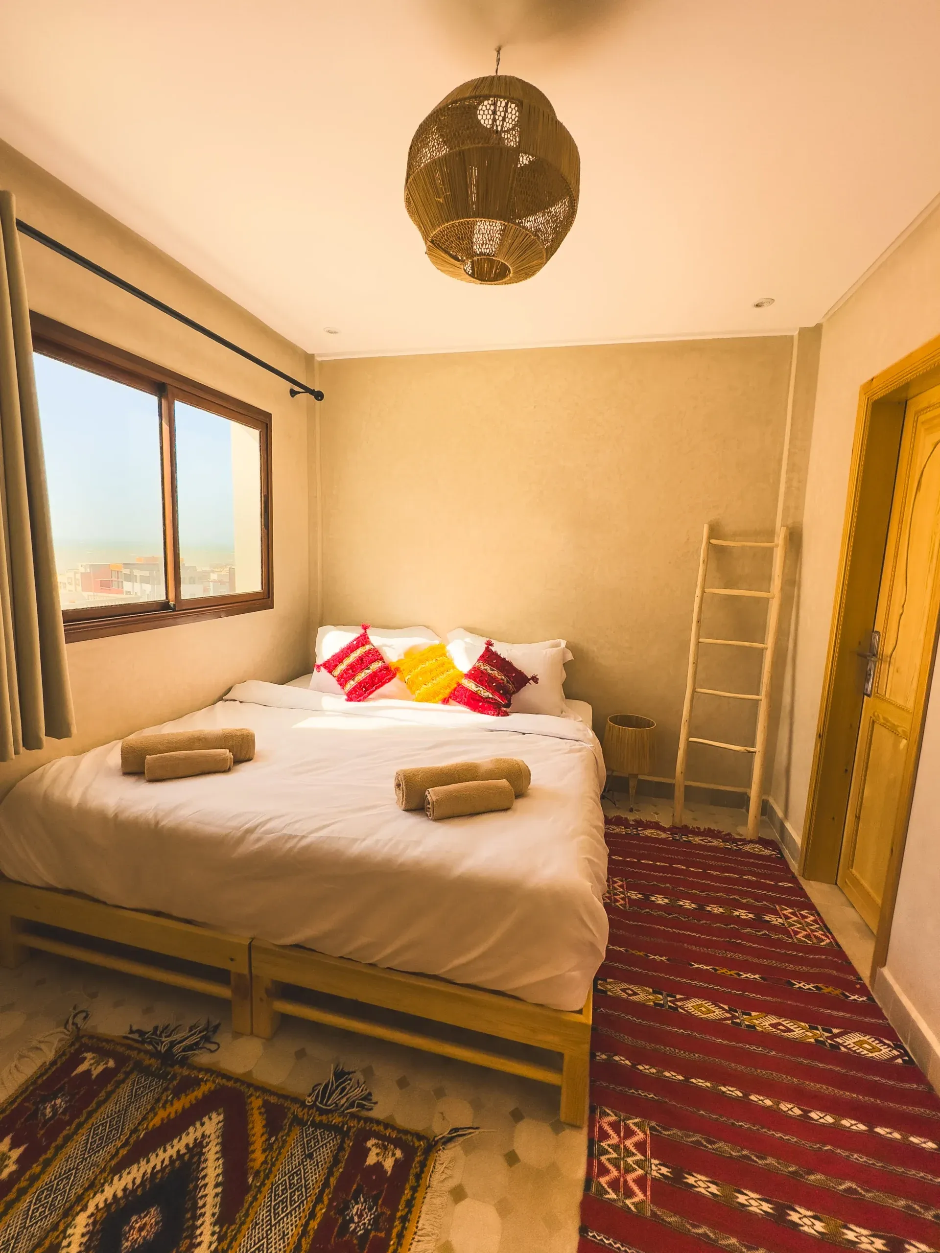 Cozy bedroom in Moroccan Surf House with colorful decor and natural light.