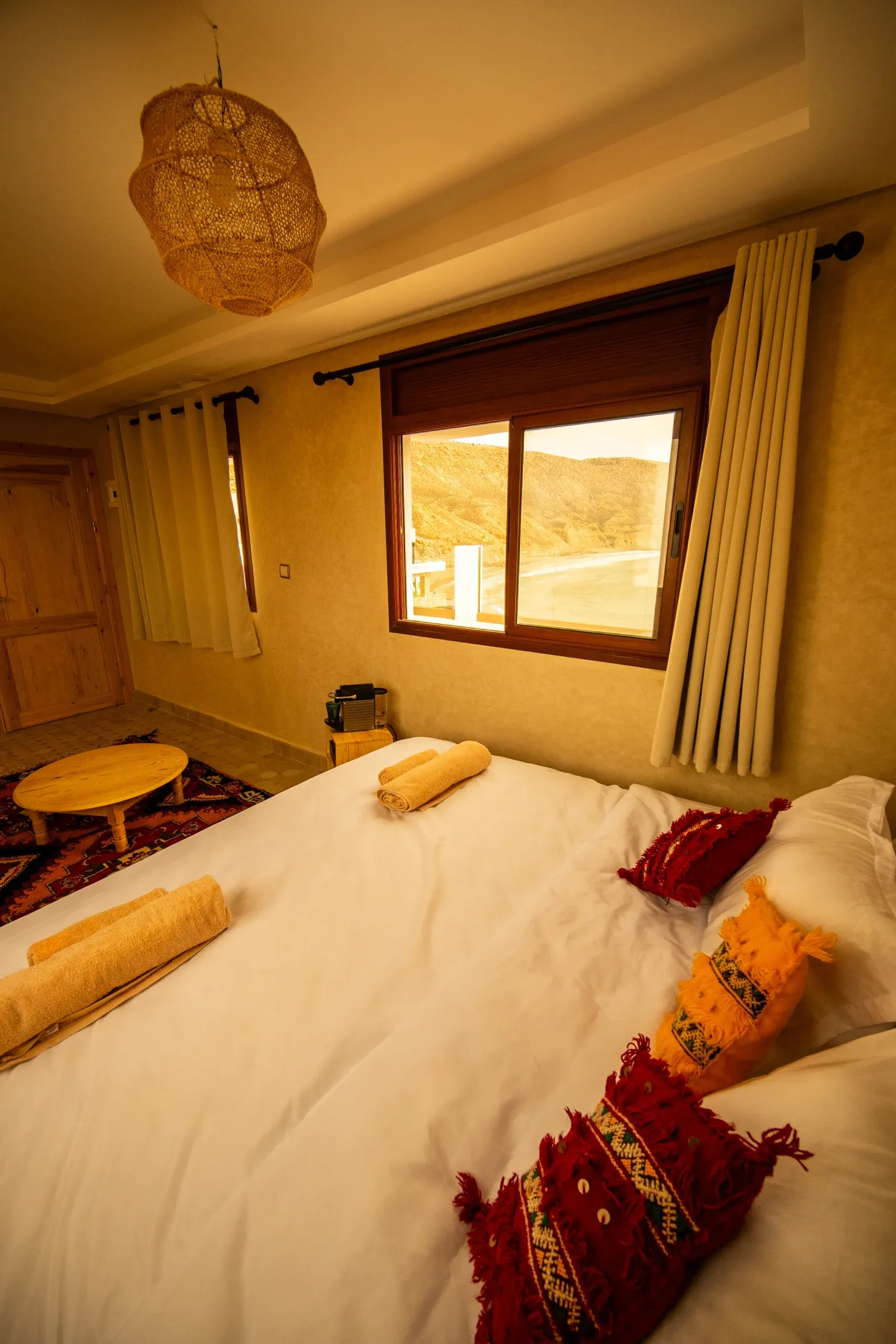 Cozy bedroom in Moroccan Surf House with colorful pillows and natural light.