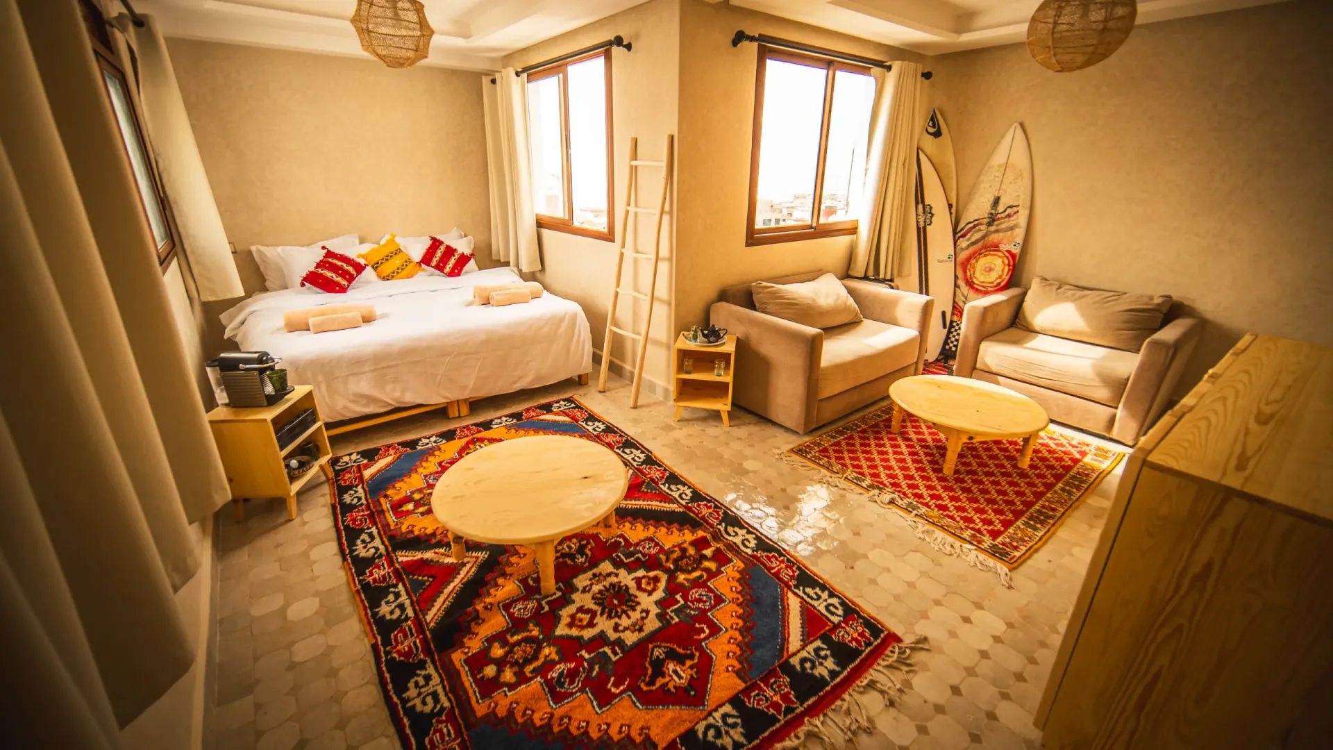 Cozy surf camp room with a bed, seating area, and surfboard.
