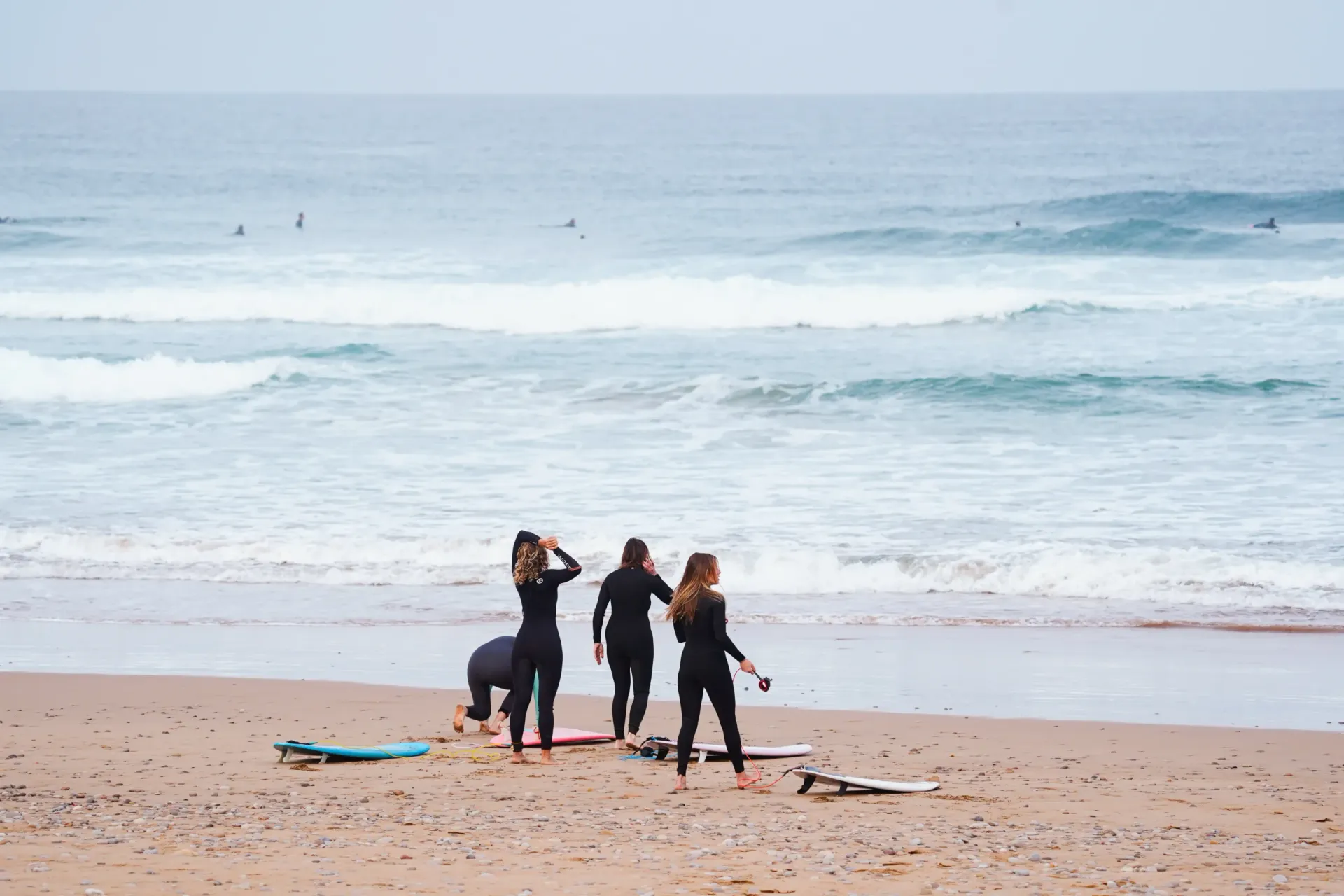 Surfers preparing on the beach at Imsouane, Morocco, with waves in the background.